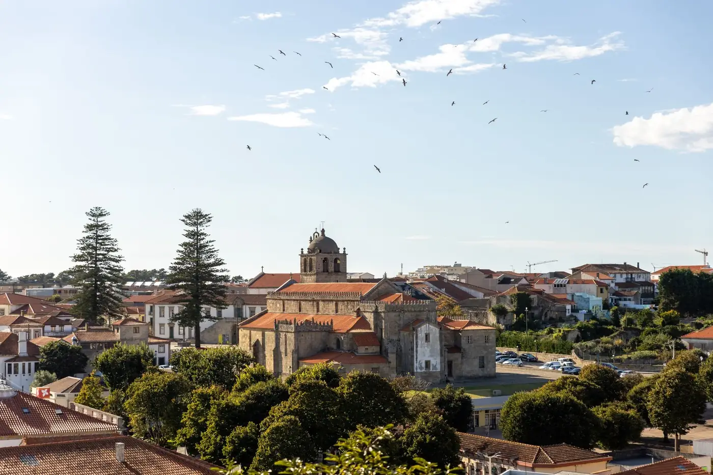 Scenic view of a historic church in Vila do Conde, Portugal with blue sky and green trees.