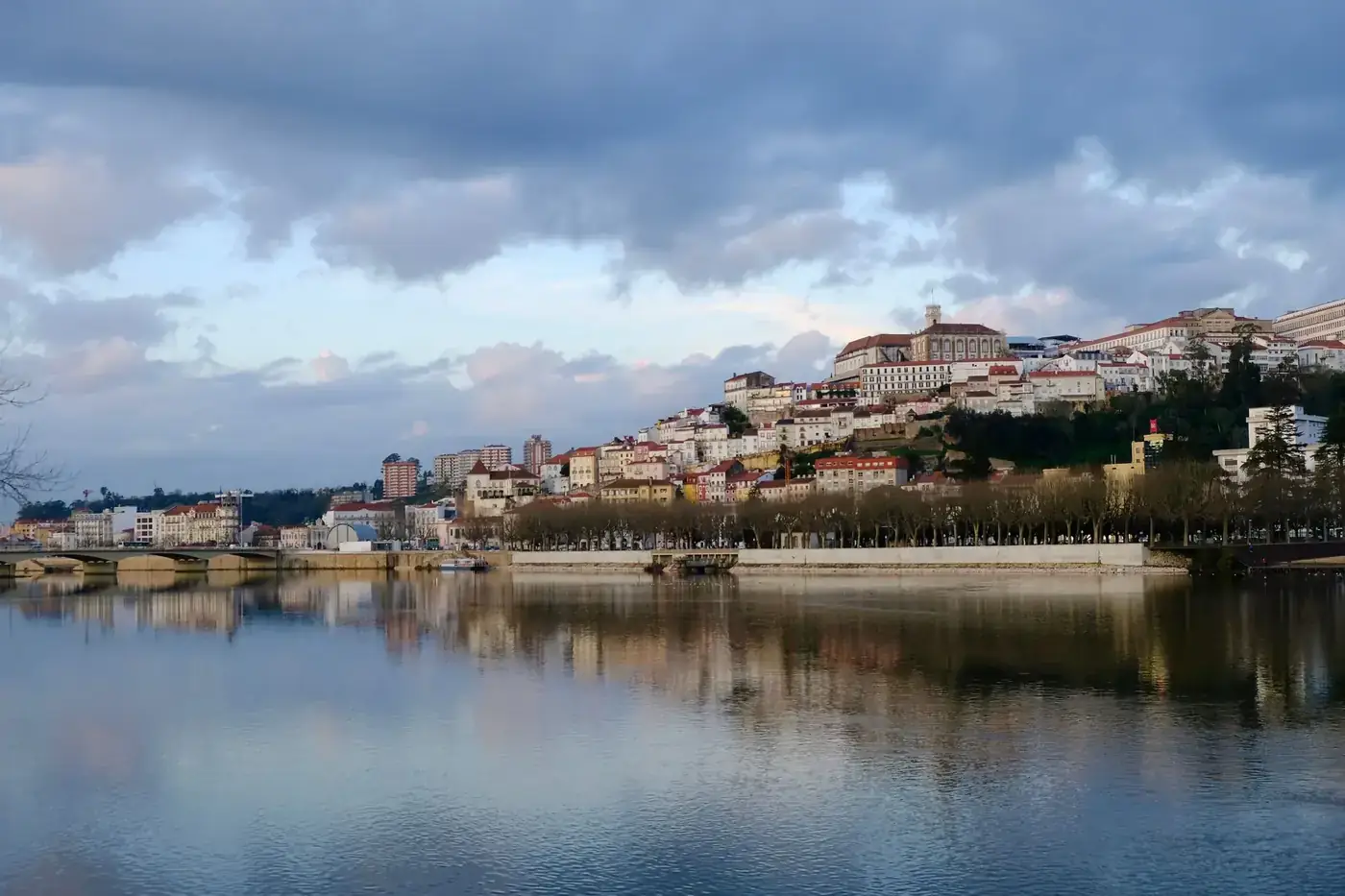 Picturesque view of a town reflecting on a calm river under a partly cloudy sky.