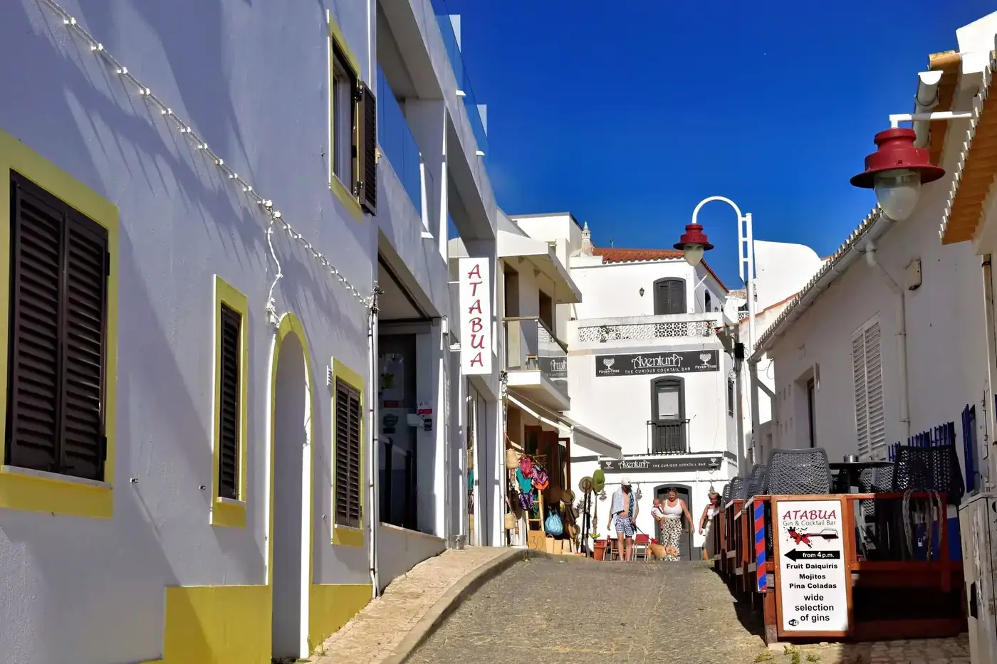 Vibrant street scene in Salema, Portugal with whitewashed buildings and shops.