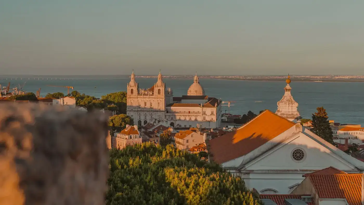 A stunning view of Lisbon showcasing historic architecture against the backdrop of the sea at sunset.