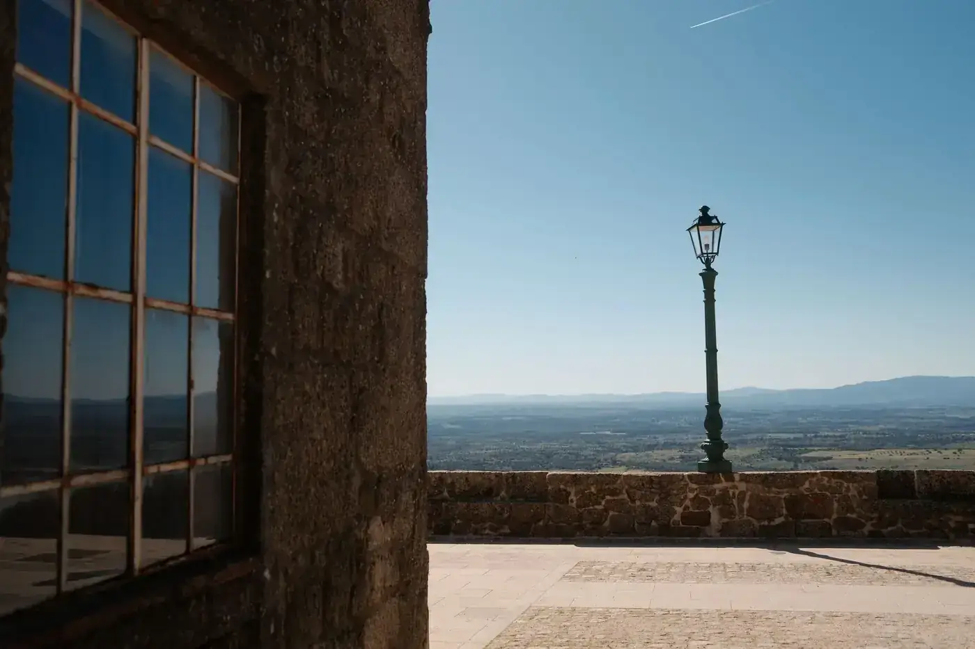 Serene landscape view from a historic stone castle in Portugal, showcasing clear blue skies and distant mountains.