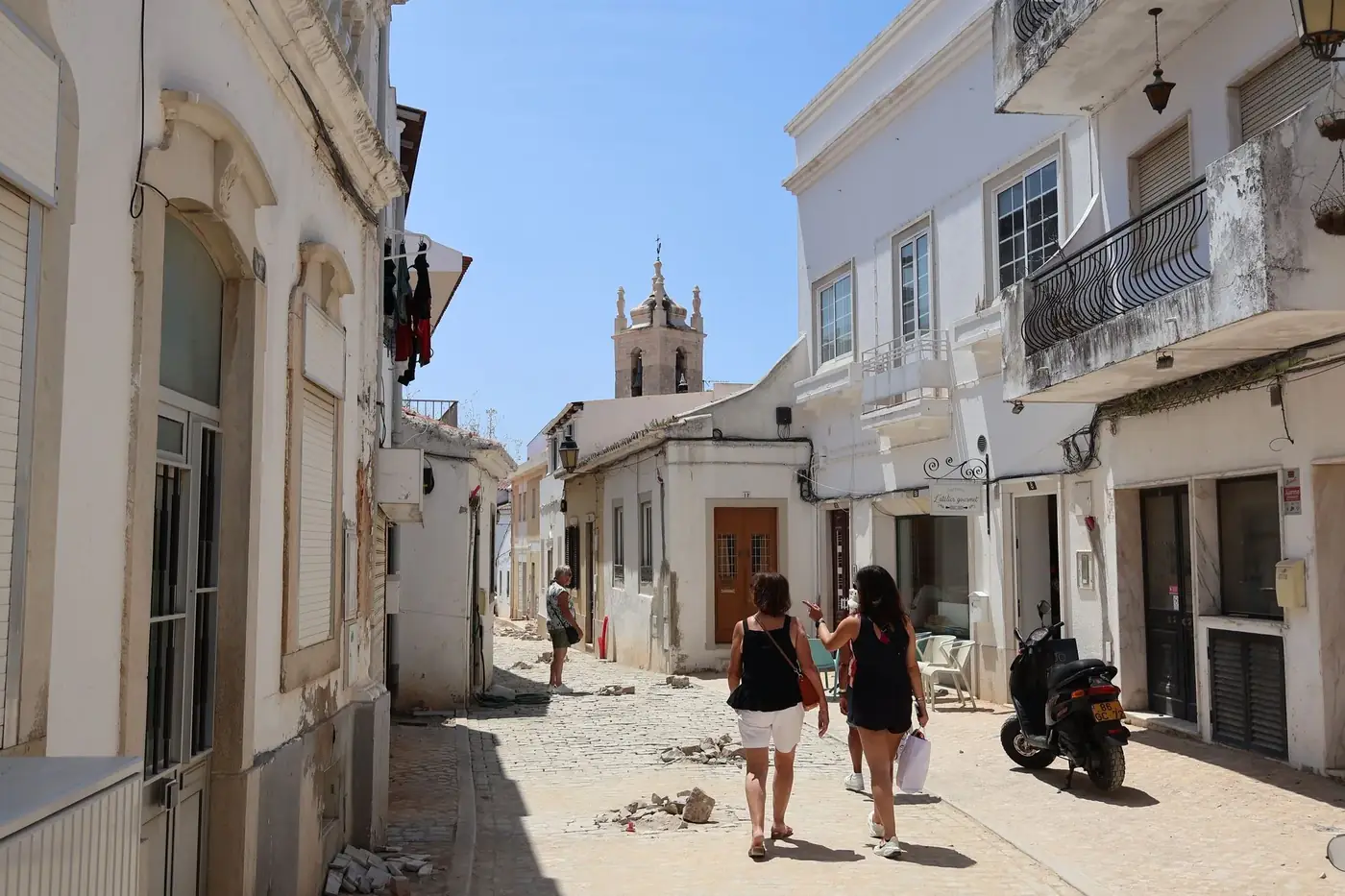 Charming cobblestone street in Tavira, Portugal, showcasing historic architecture under a bright summer sky.
