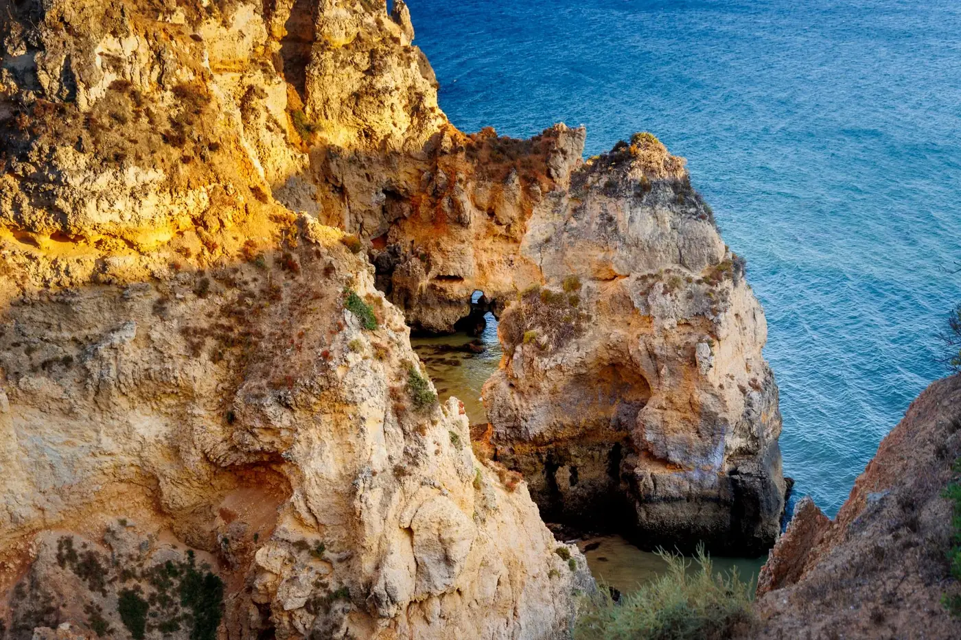 Explore the stunning cliffs of Praia do Camilo in Lagos, Portugal, bathed in sunlight beside the azure sea.
