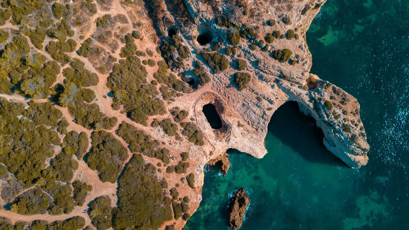 Aerial view of rugged coastline with eroded rock formations and turquoise sea water.