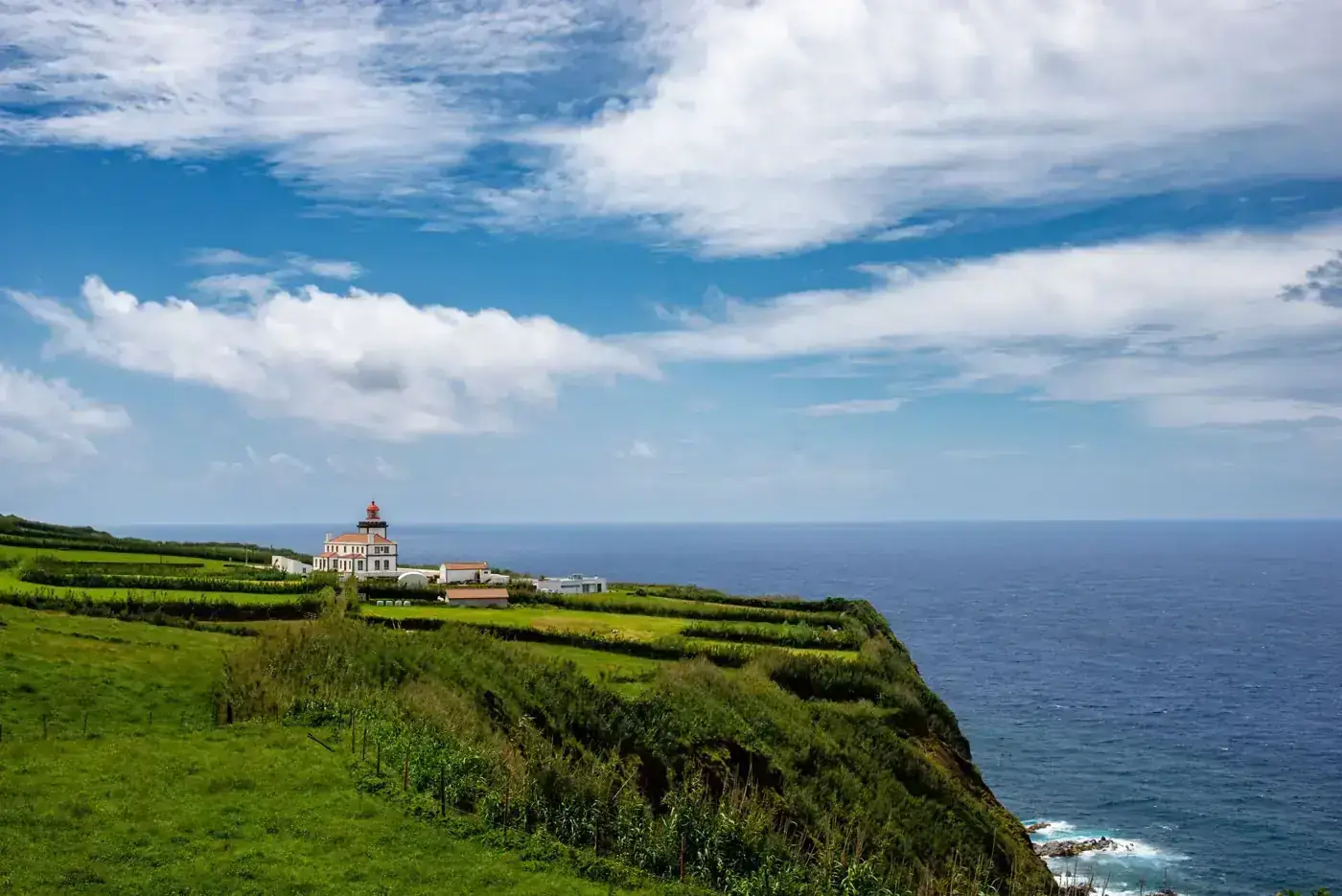 Picturesque lighthouse with lush greenery and ocean view on São Miguel Island, Azores.