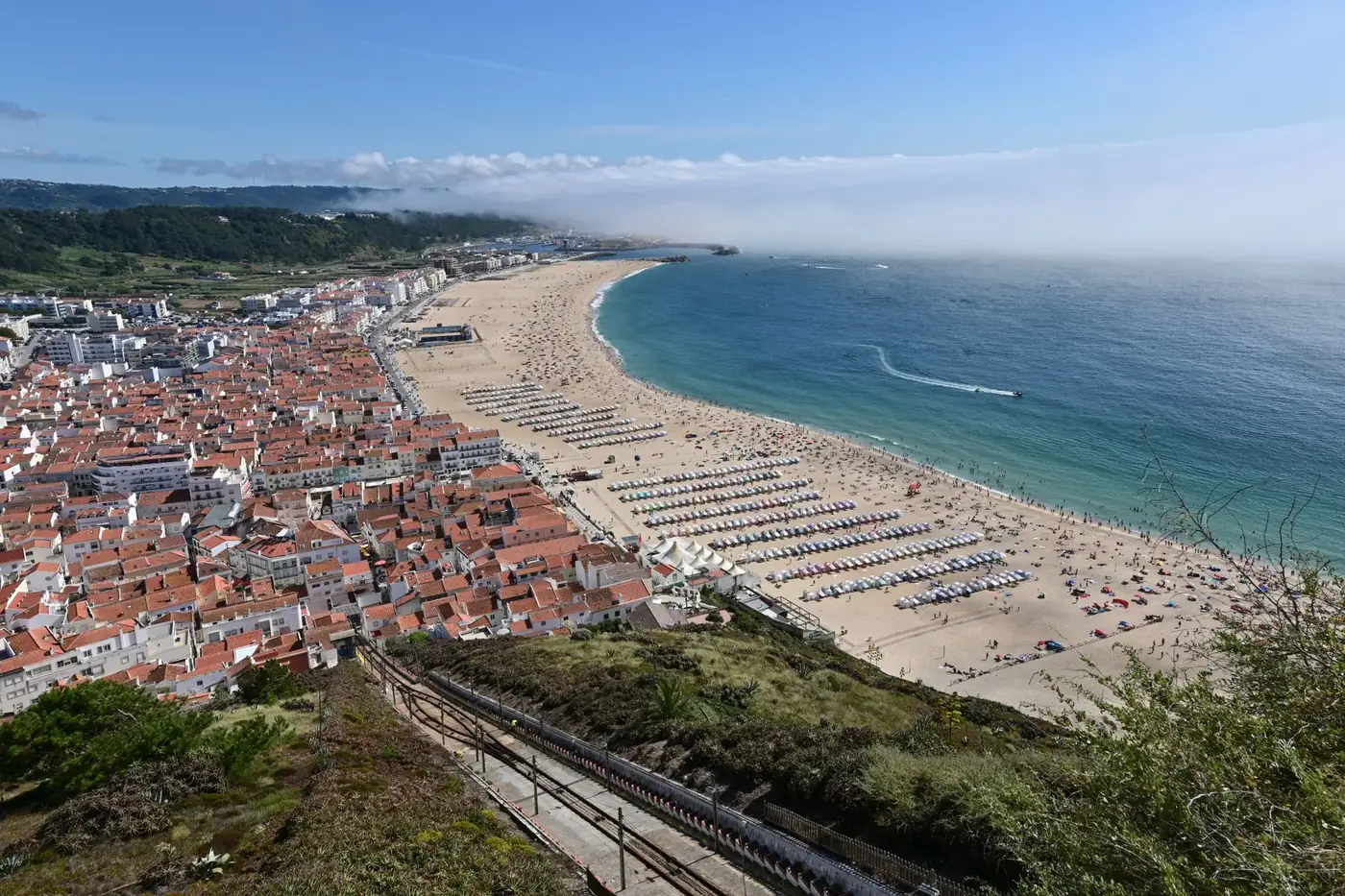 Explore the breathtaking aerial view of Nazaré Beach with its stunning coastline and vibrant seaside town.