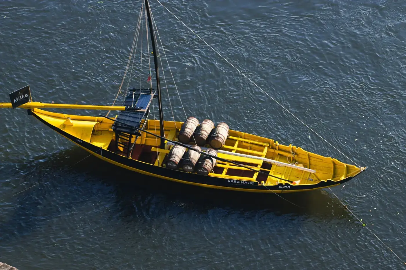 A vibrant yellow Rabelo boat carrying barrels on the Douro River in Porto, Portugal.