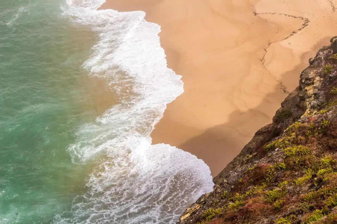 Dramatic waves crashing on the sandy shores of Nazaré beach, Portugal.